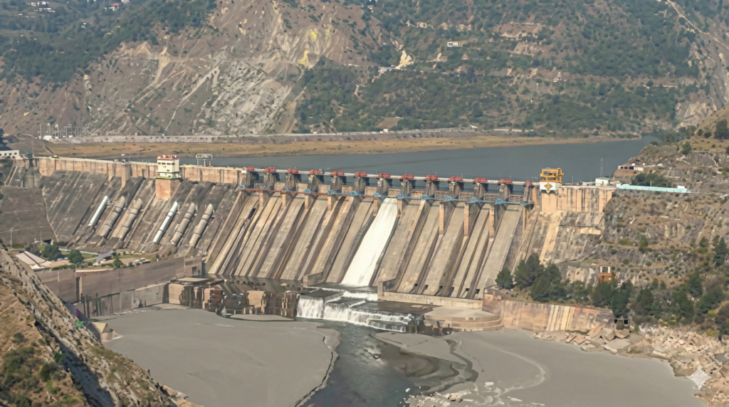 Aerial view of Salal Dam on the Chenab River featuring heavy machinery performing mechanical desilting and dredging operations to remove accumulated sediment.