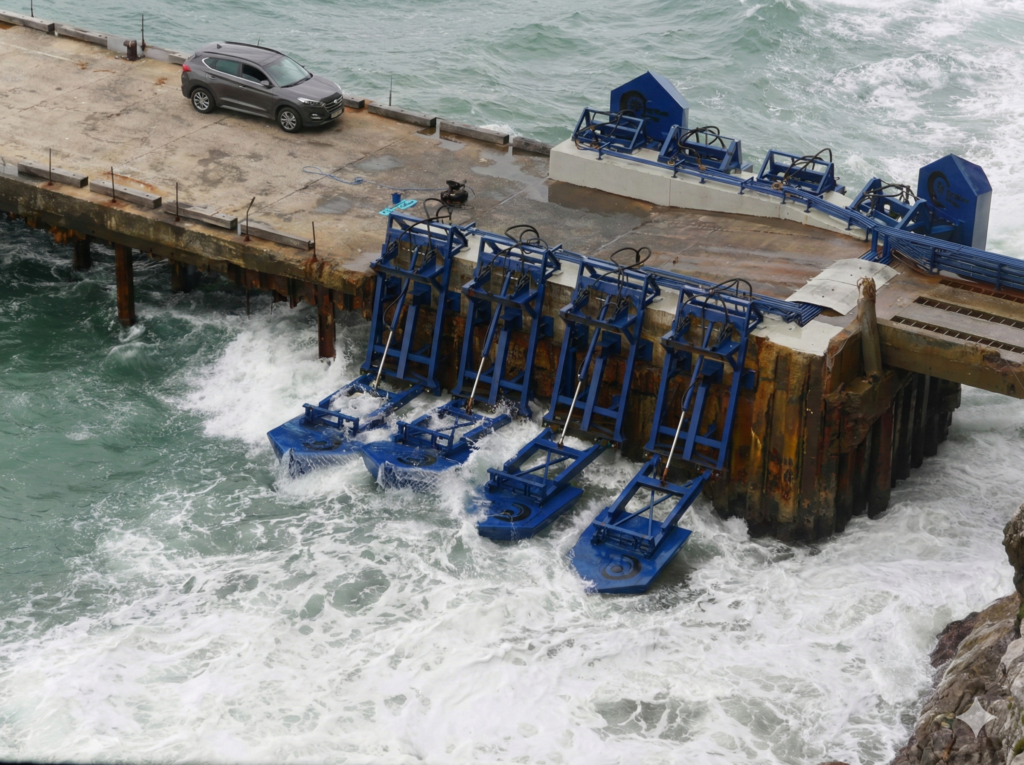 कूबरखा के पोर्ट ऑफ एंगकुरा में समुद्र की ऊँची लहरें और ब्रेकवाटर दीवार, जहाँ वेव एनर्जी पावर स्टेशन बनाने का प्रस्ताव है। (Ocean waves at Port of Ngqura, Gqeberha, proposed site for wave energy station).